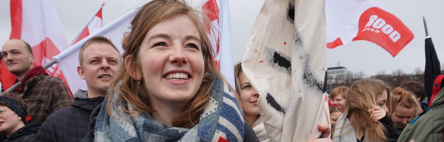 Lachende student met vlag in de hand bij een demonstratie